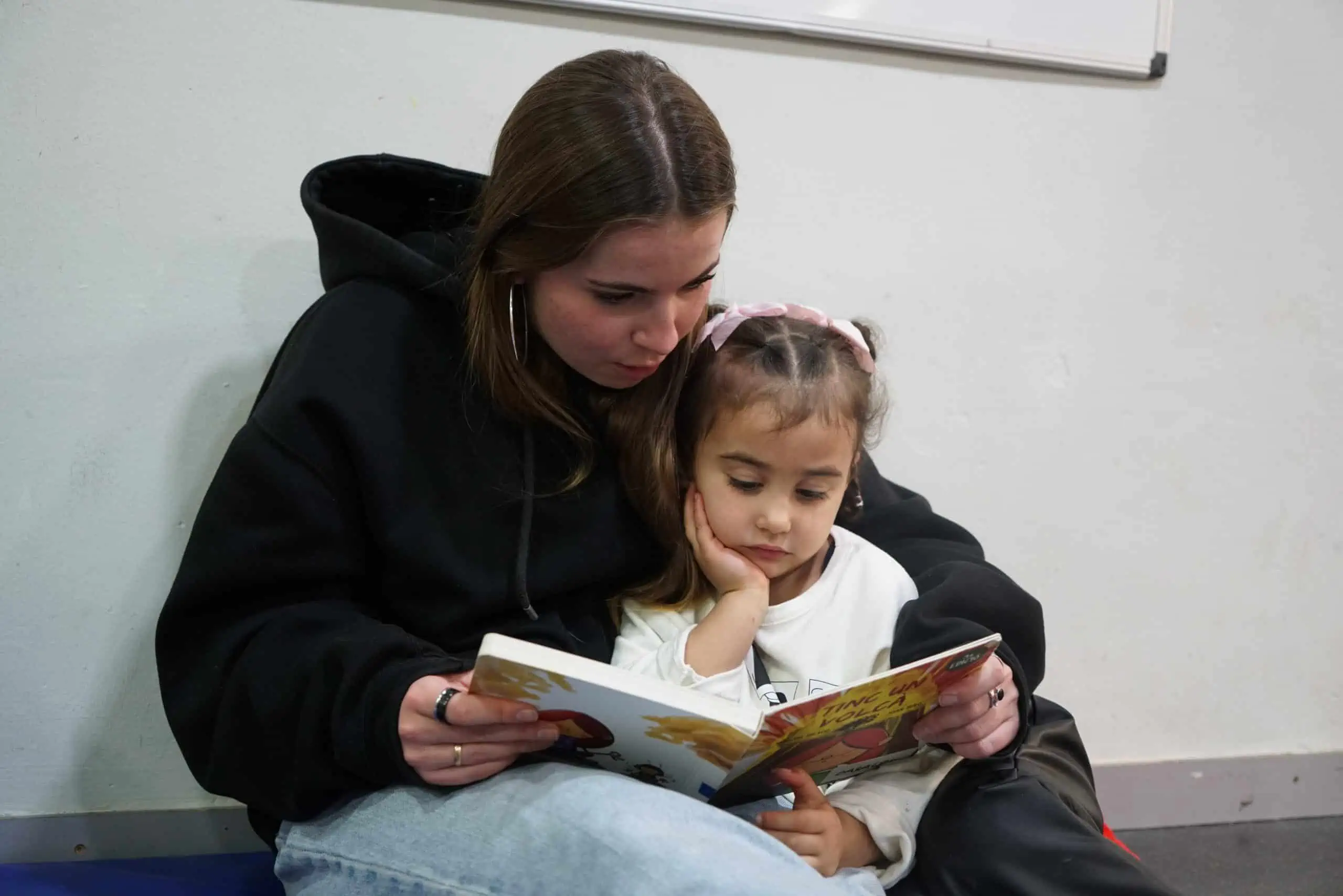 An adult and a child reading a book together